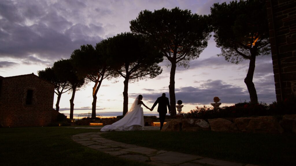 a bride and groom hand in hand walking at sunset in tuscany