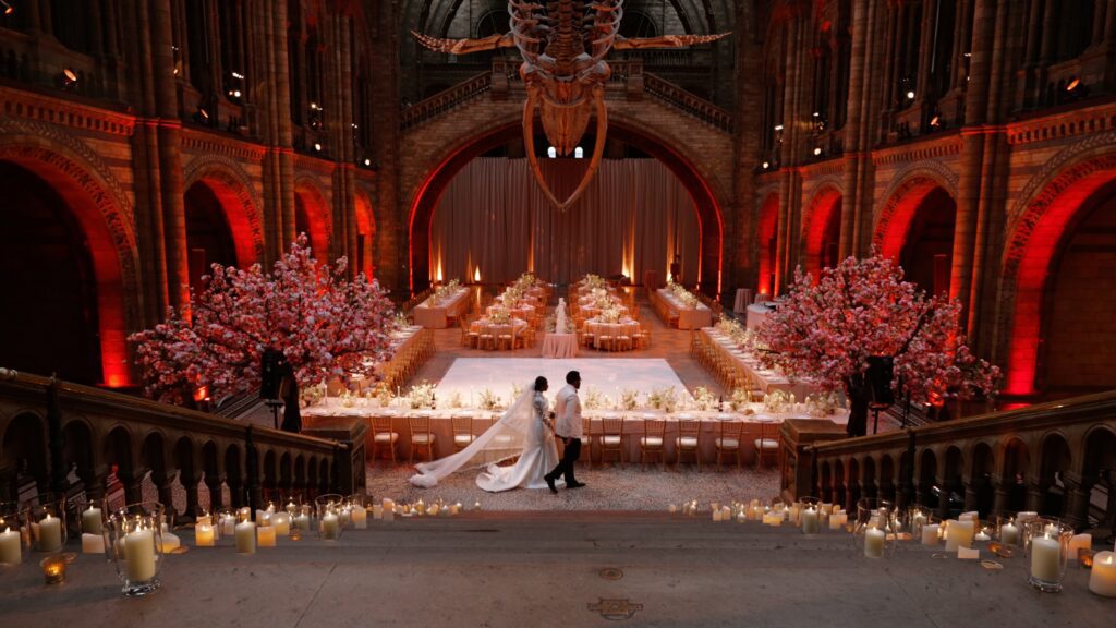 a bride and groom walking around hintze hall in the natural history museum